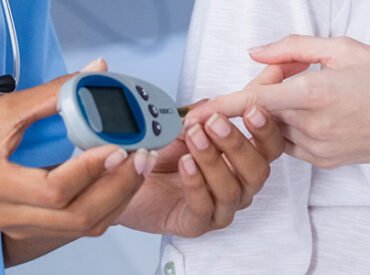 Doctor examining pregnant womans blood sugar in hospital